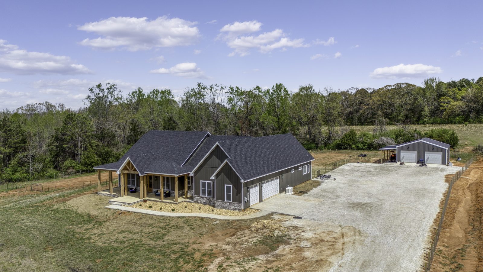 The Stone Craftsman aerial view with attached garage, driveway and detached shop