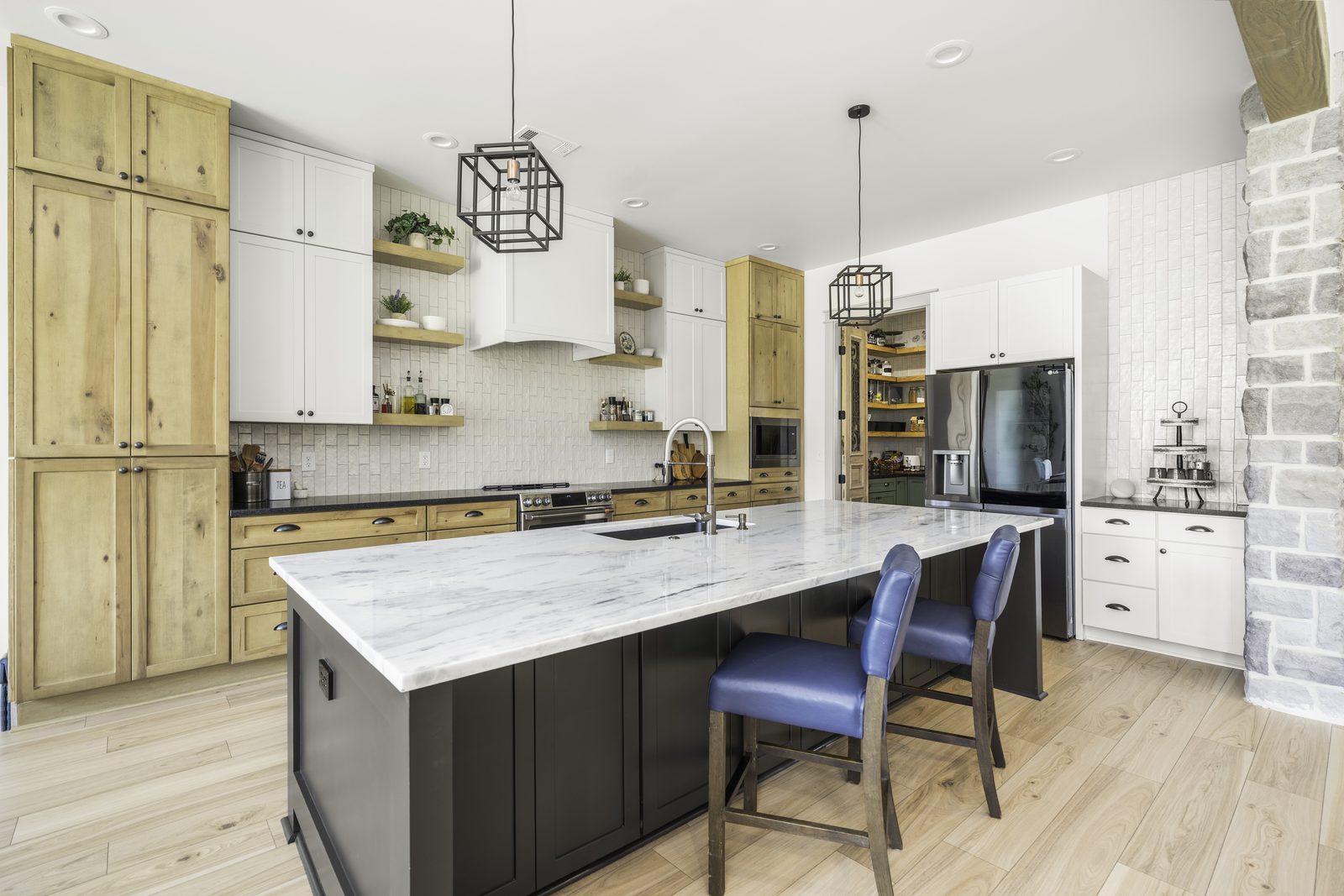 The Stone Craftsman kitchen with quartz island, blue bar stools and natural wood cabinets