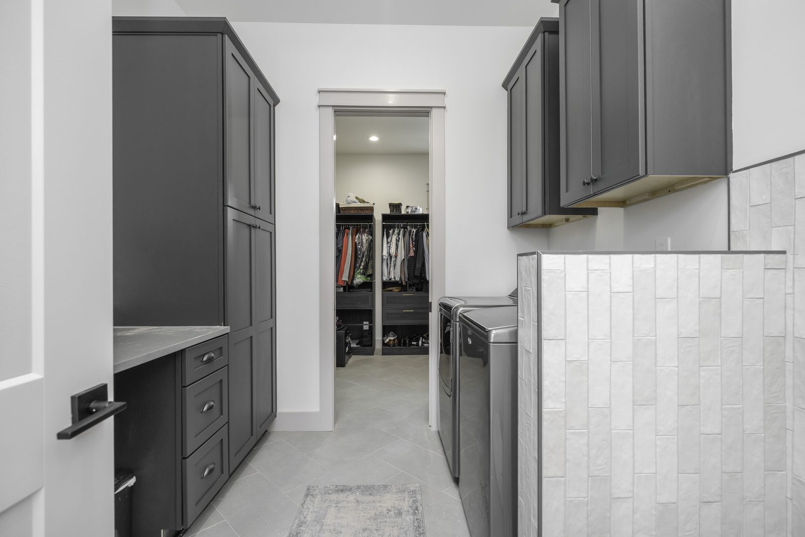 The Stone Craftsman laundry room with gray cabinets, looking into the walk-in closet