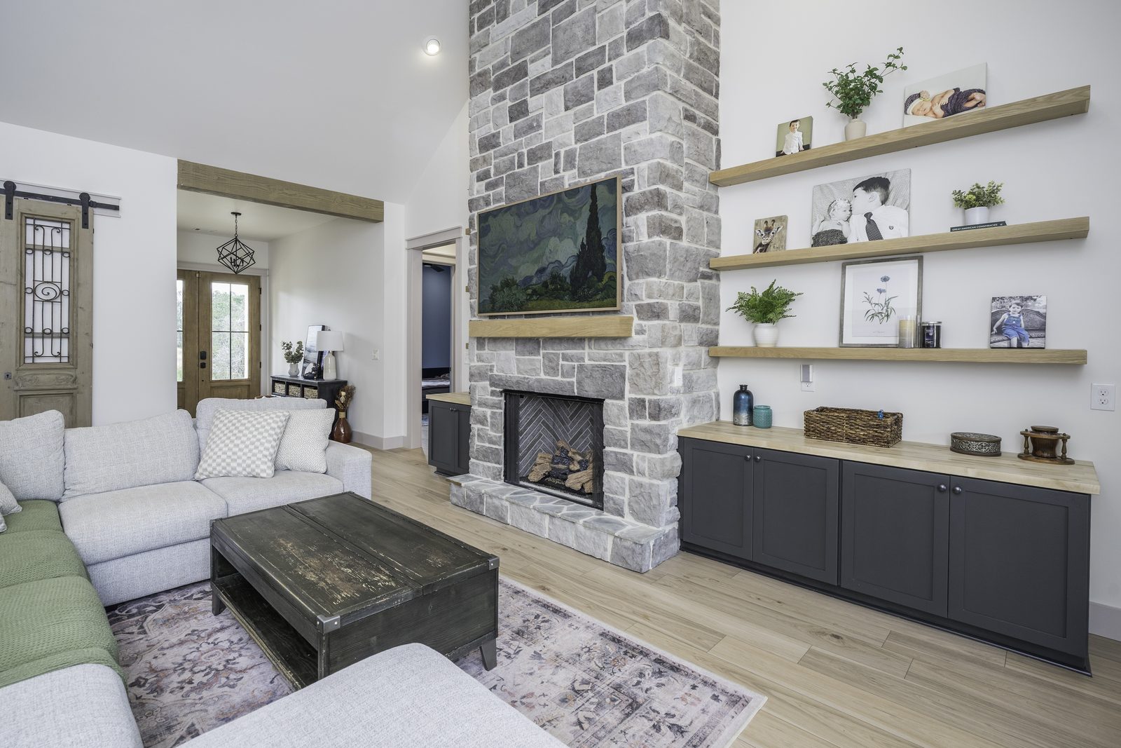 The Stone Craftsman living room with stone fireplace and floating wood shelves