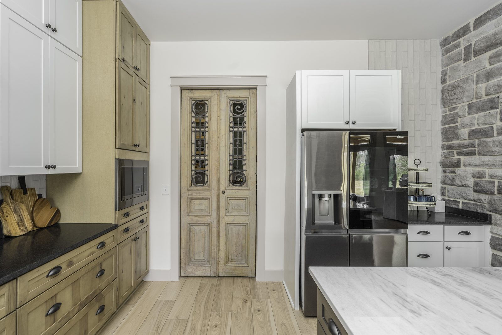 The Stone Craftsman kitchen with vintage-style pantry door and stone accent wall
