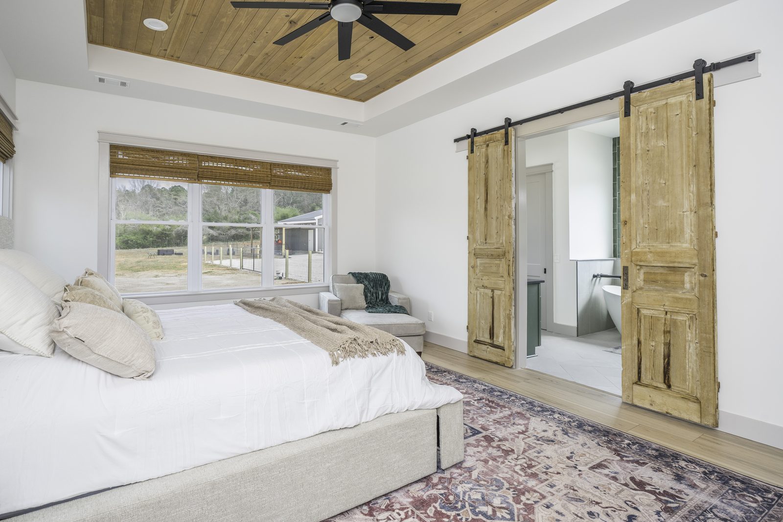 The Stone Craftsman primary bedroom with sliding barn doors to the bath