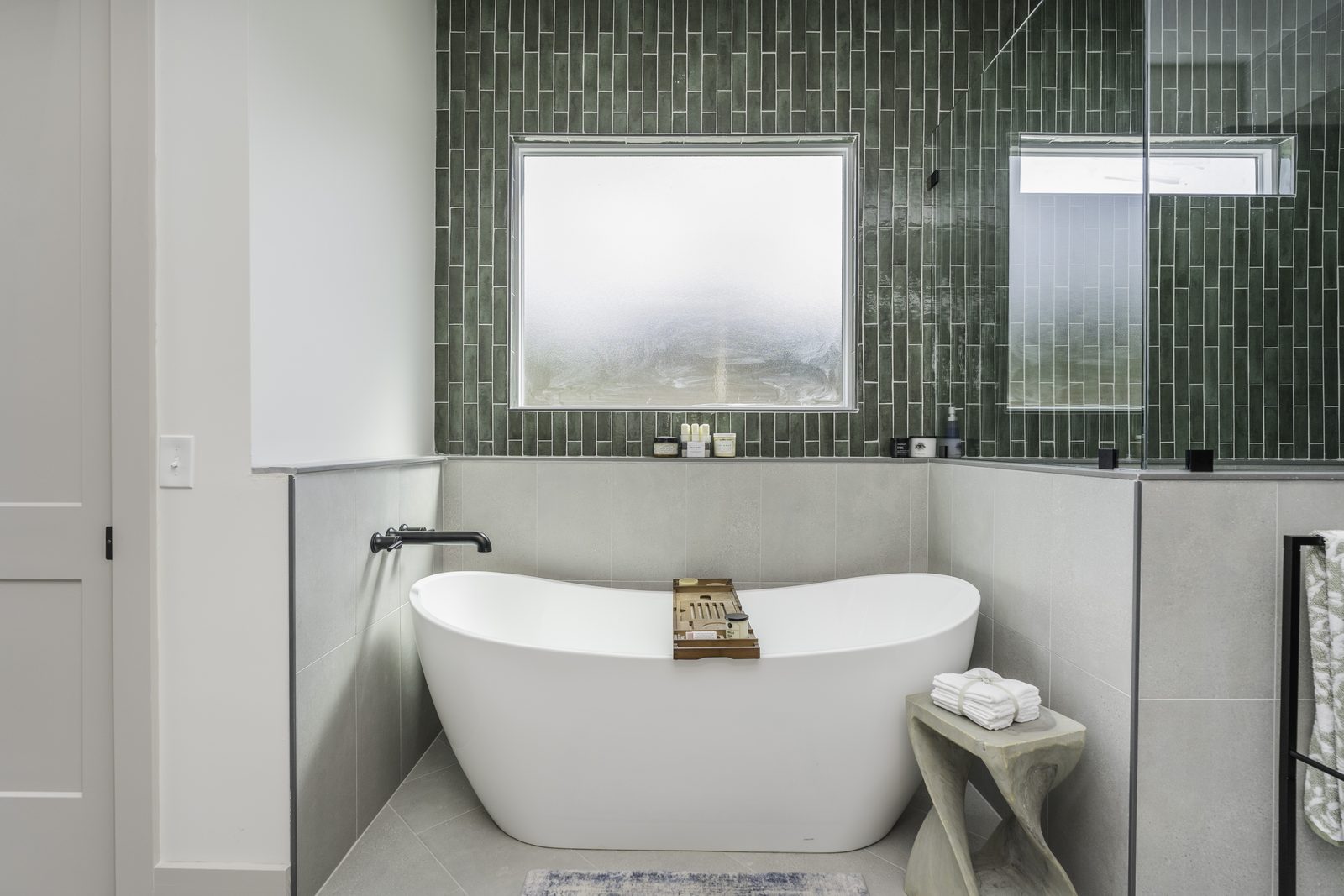 The Stone Craftsman primary bath freestanding tub under a frosted window