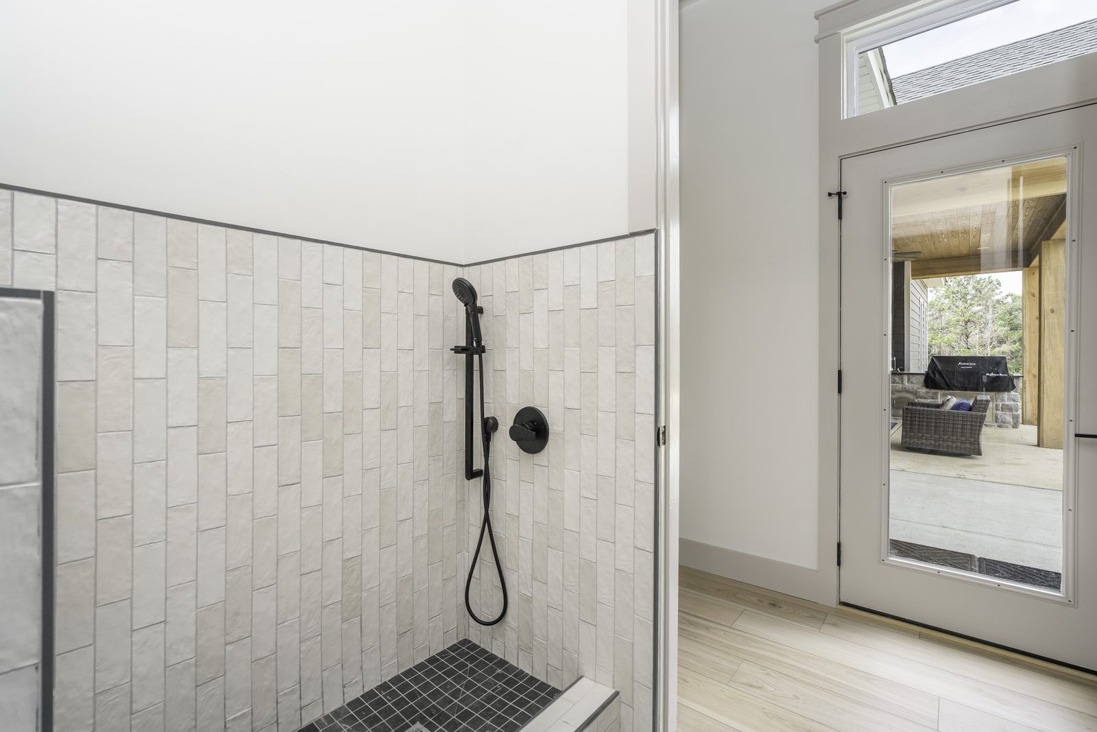 The Stone Craftsman tiled walk-in shower beside a glass back door