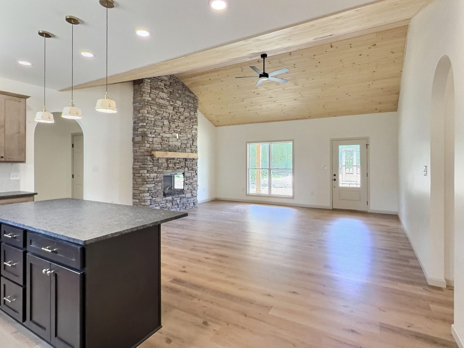 The Cedar Ranch open living room and kitchen with stacked stone fireplace