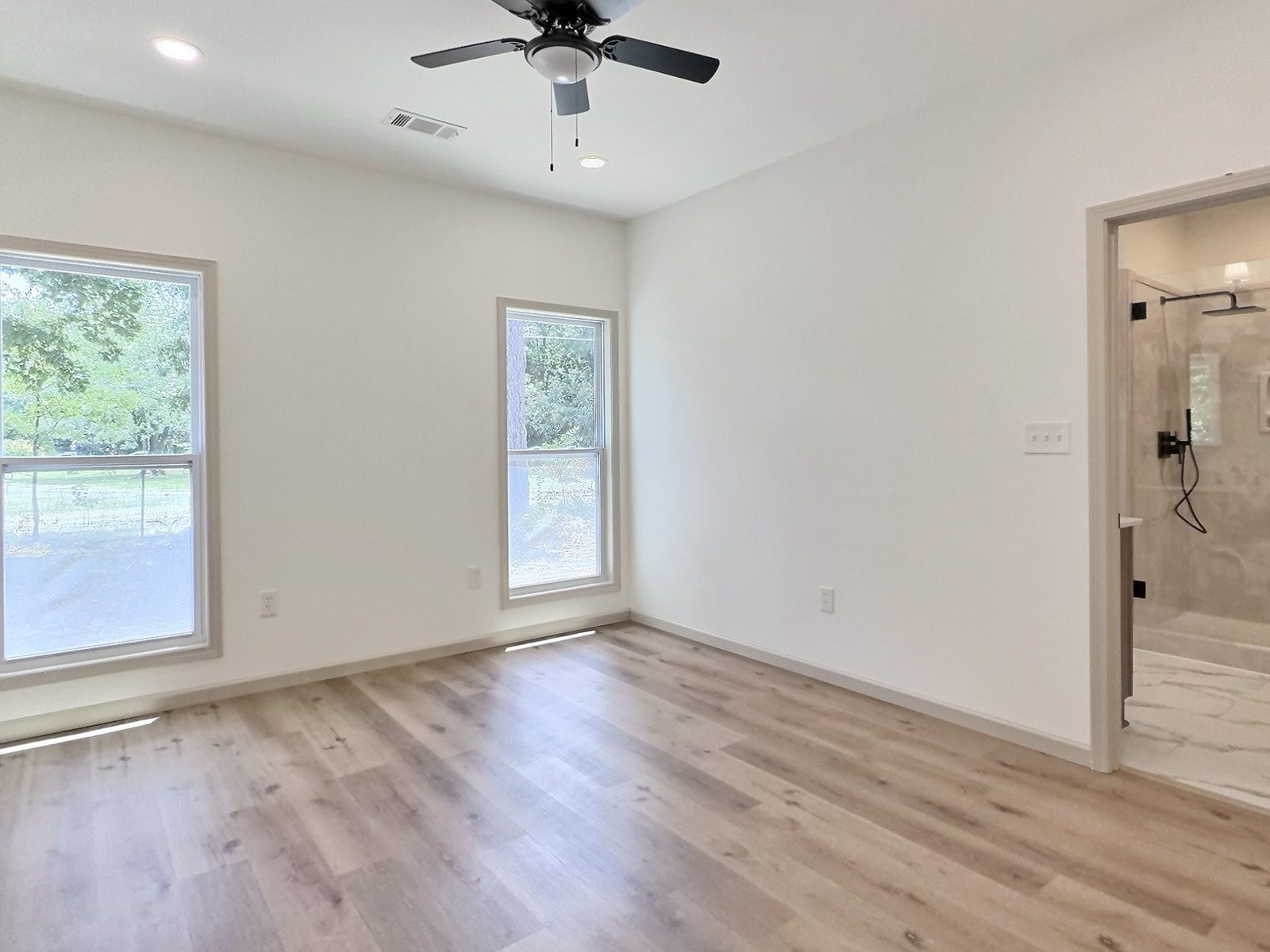 The Cedar Ranch primary bedroom with ceiling fan and view into the bath