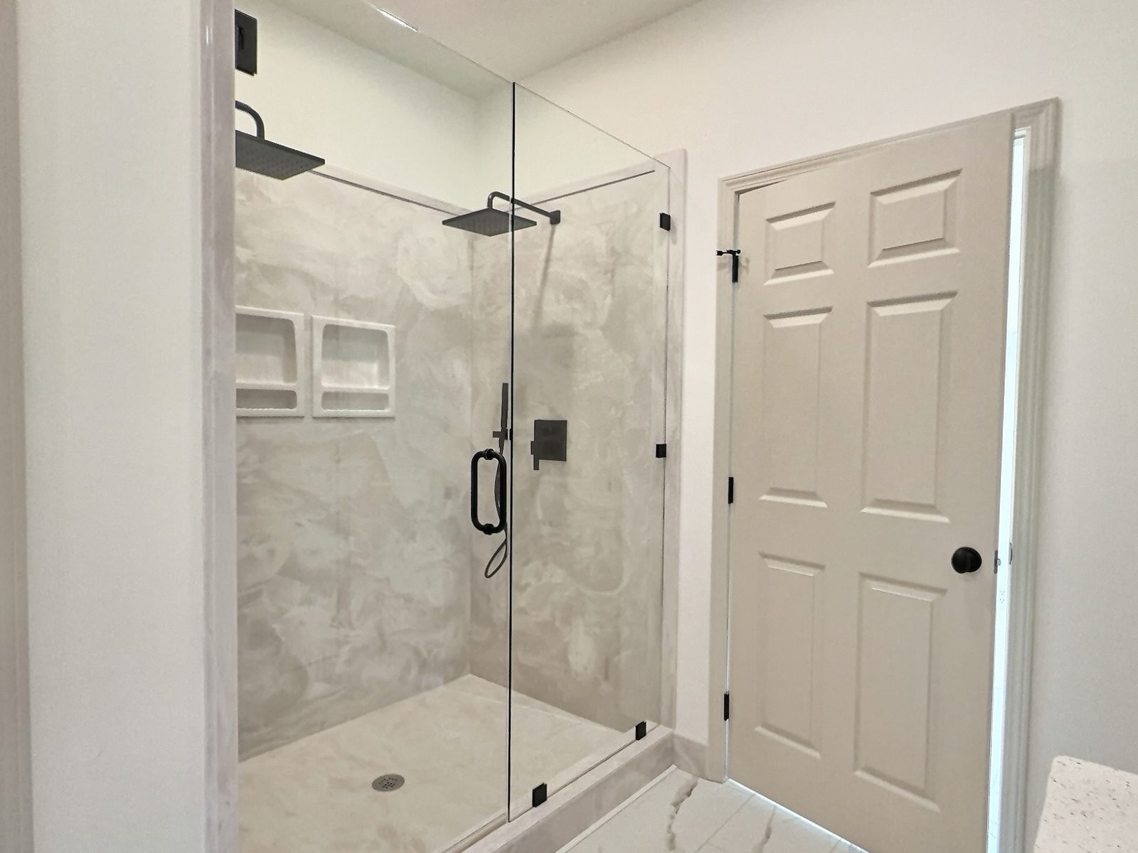 The Cedar Ranch primary bath glass walk-in shower with niches