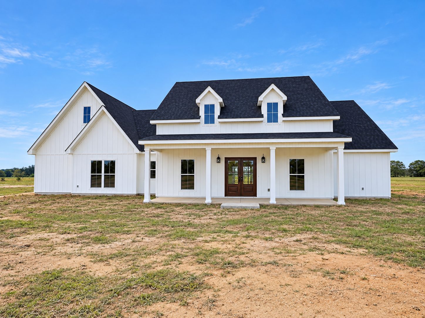 The White Farmhouse exterior with board-and-batten siding, dormers and covered front porch