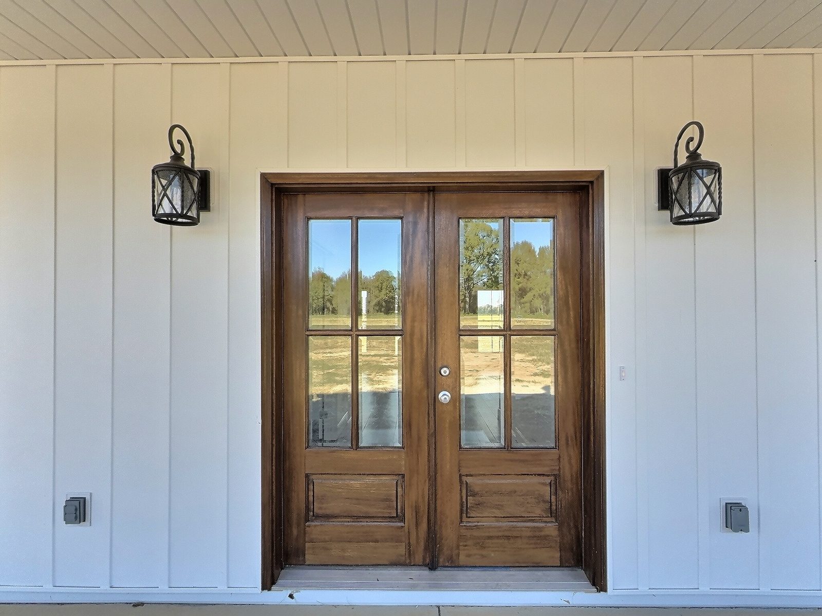The White Farmhouse wood double front doors with lantern sconces