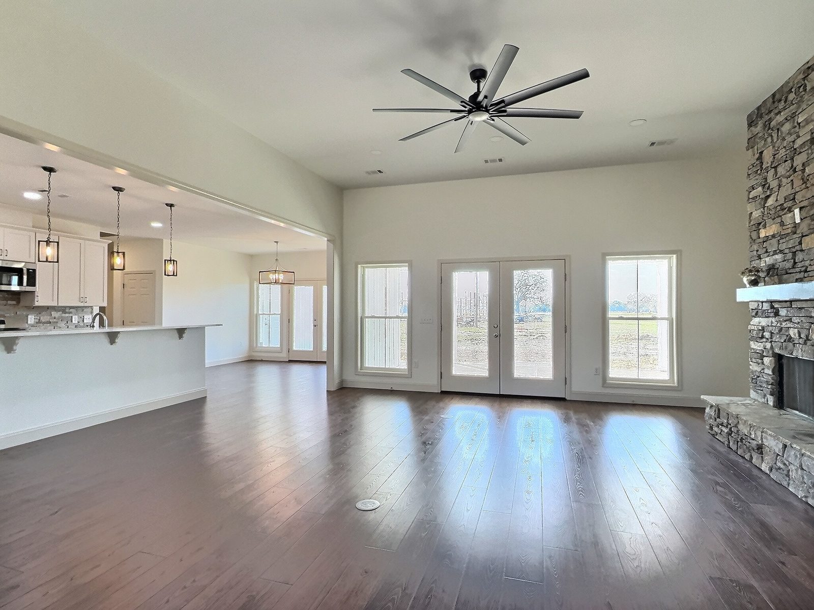The White Farmhouse open living room with stone fireplace and large windows