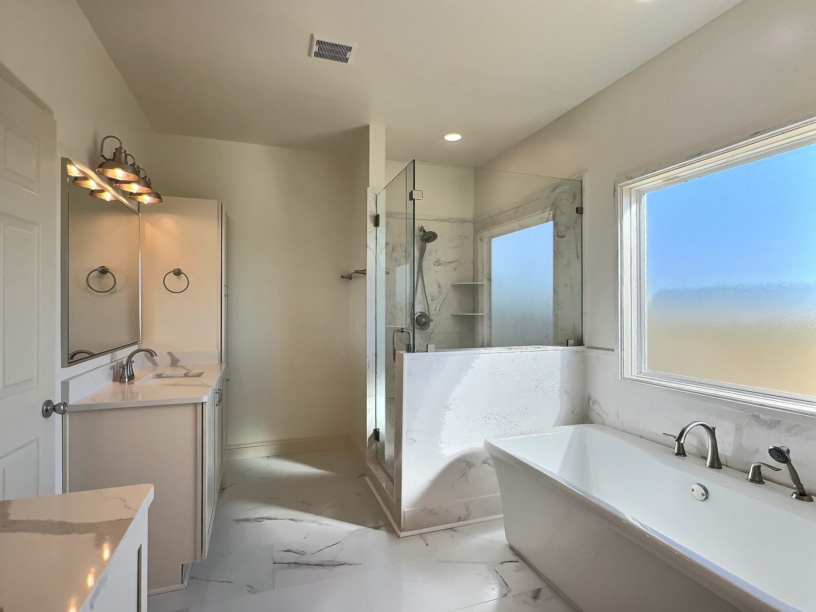 The White Farmhouse primary bath vanity, glass shower and freestanding tub