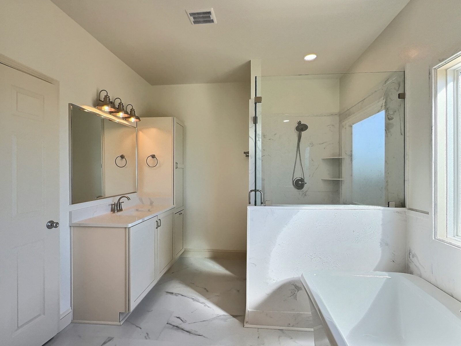 The White Farmhouse primary bath glass shower and tub