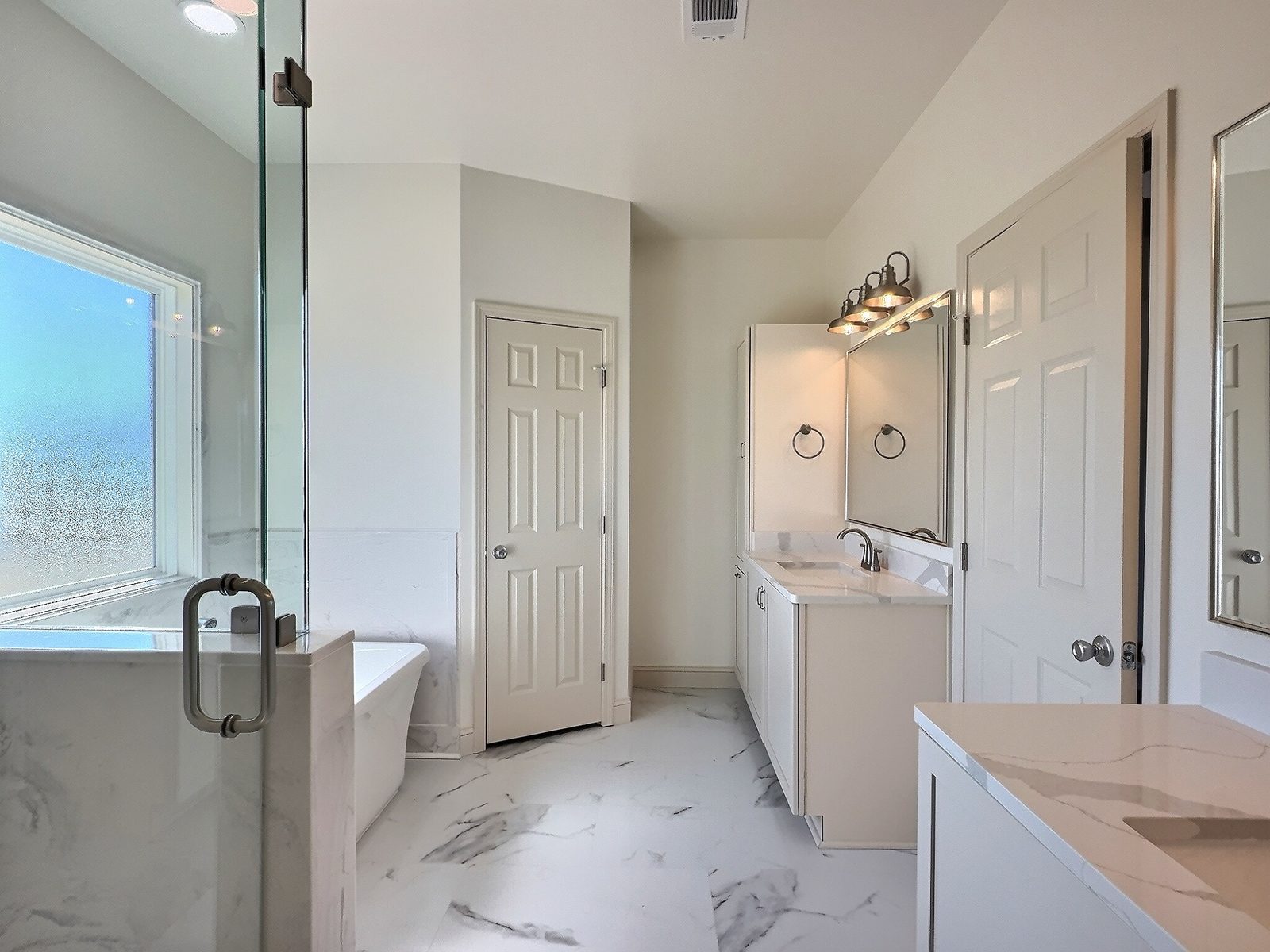 The White Farmhouse primary bath glass shower looking toward the vanity