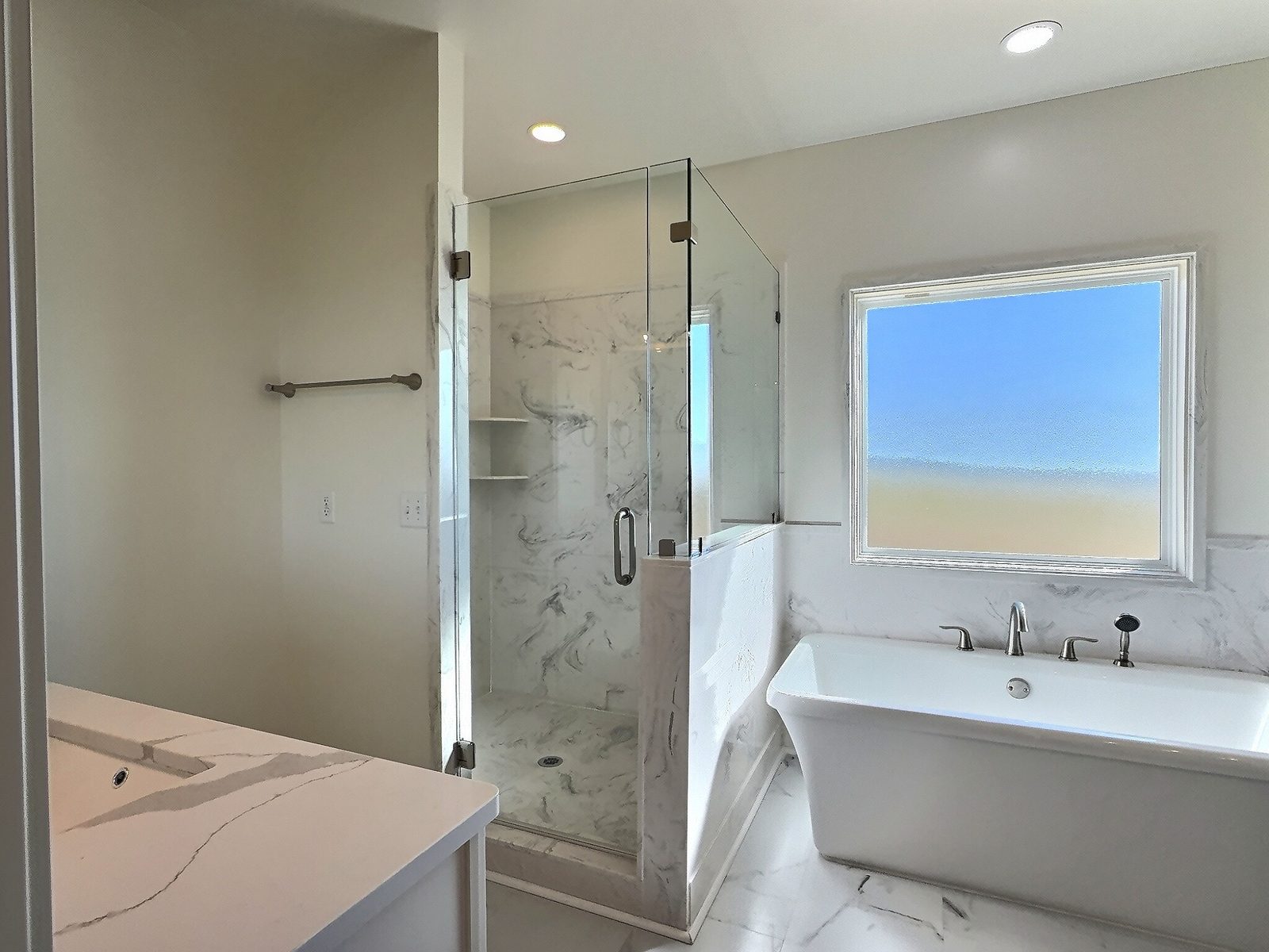 The White Farmhouse primary bath with glass shower and freestanding tub