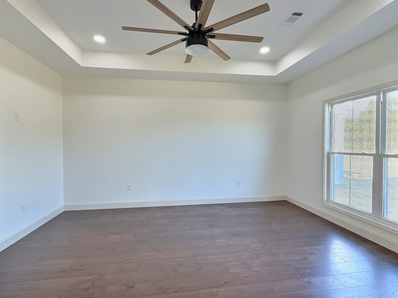 The White Farmhouse primary bedroom with tray ceiling and corner windows