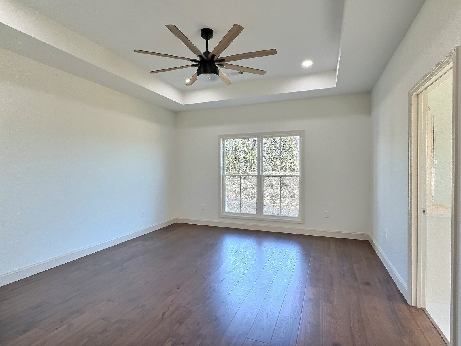 The White Farmhouse primary bedroom with tray ceiling and ceiling fan